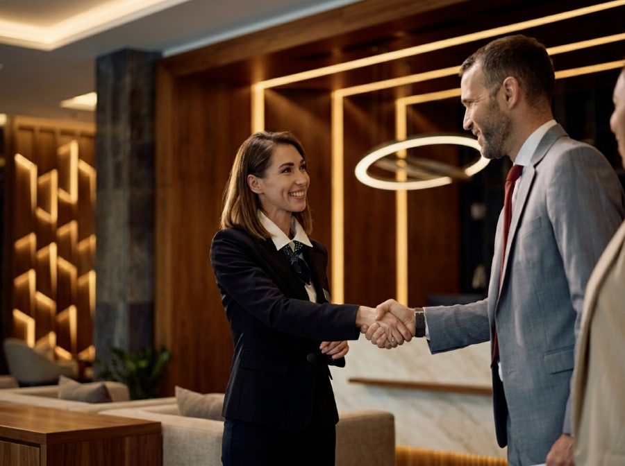 Recepcionista de hotel saludando a un agente corporativo en el lobby